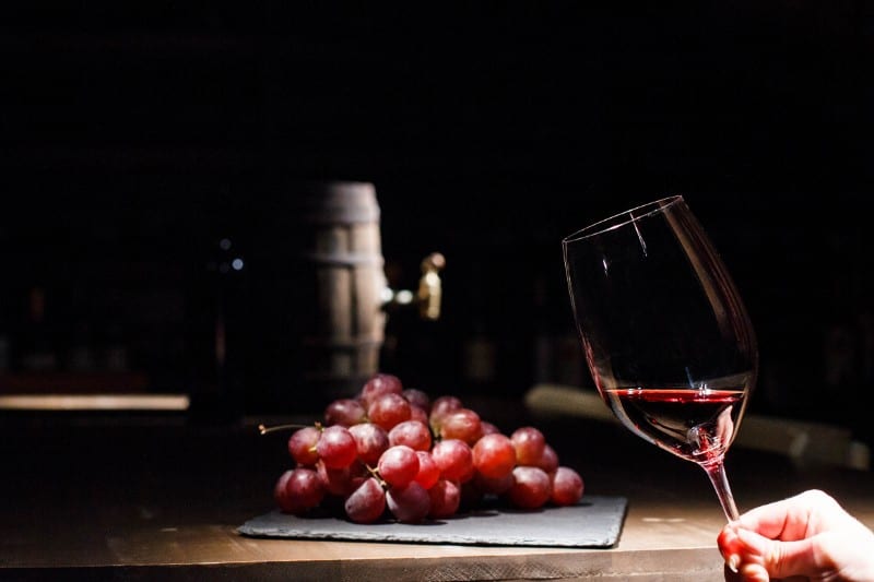 Glass of red wine with grapes on a barrel