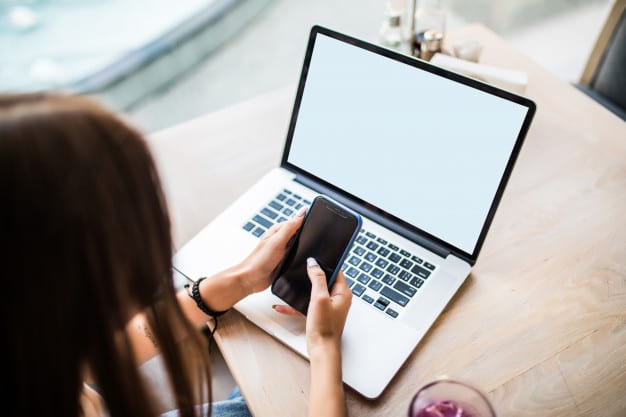 Woman using phone and laptop